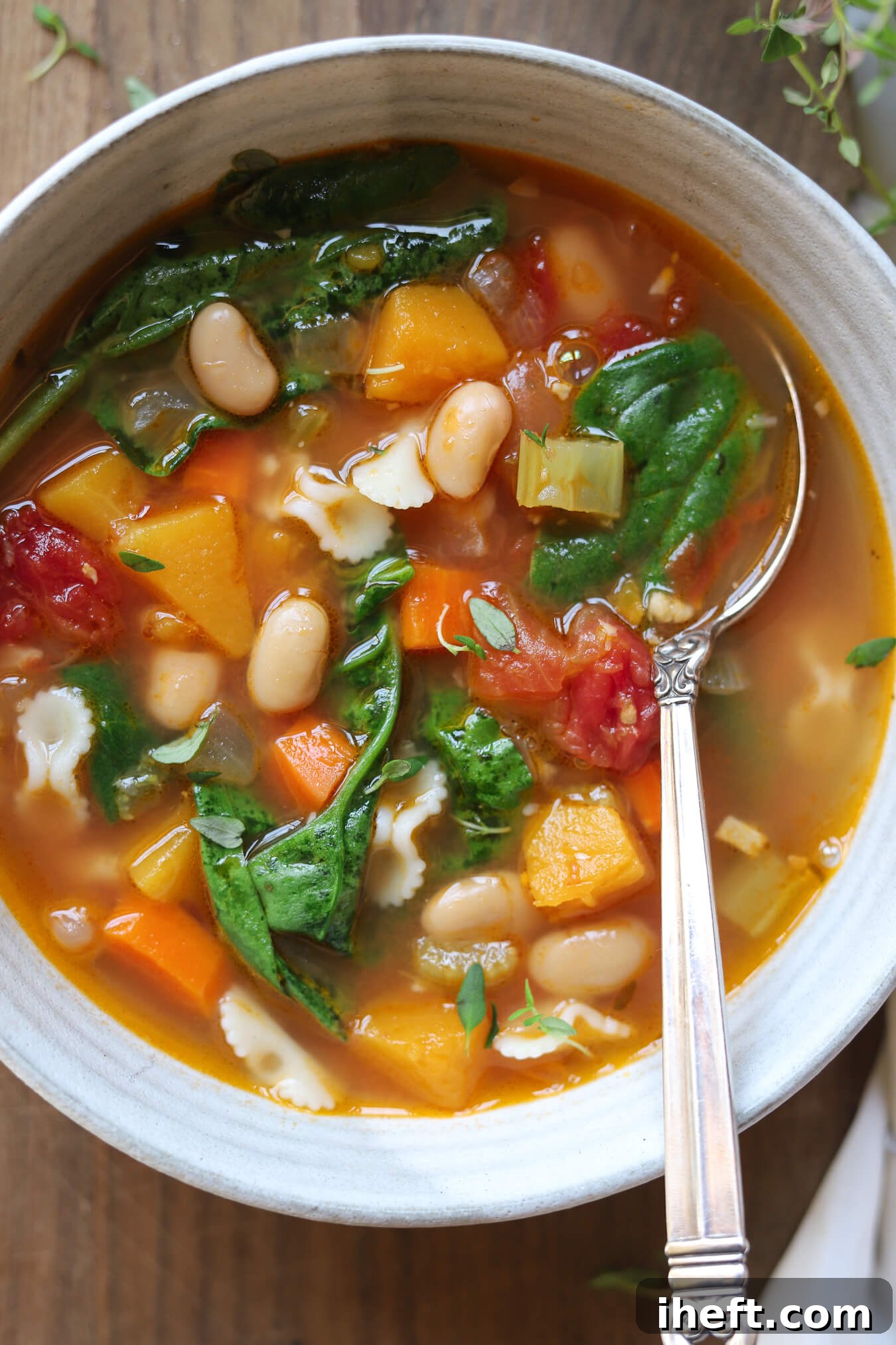 A close-up photo of a bowl of Ina Garten's winter minestrone with butternut squash, cannellini beans, and spinach.