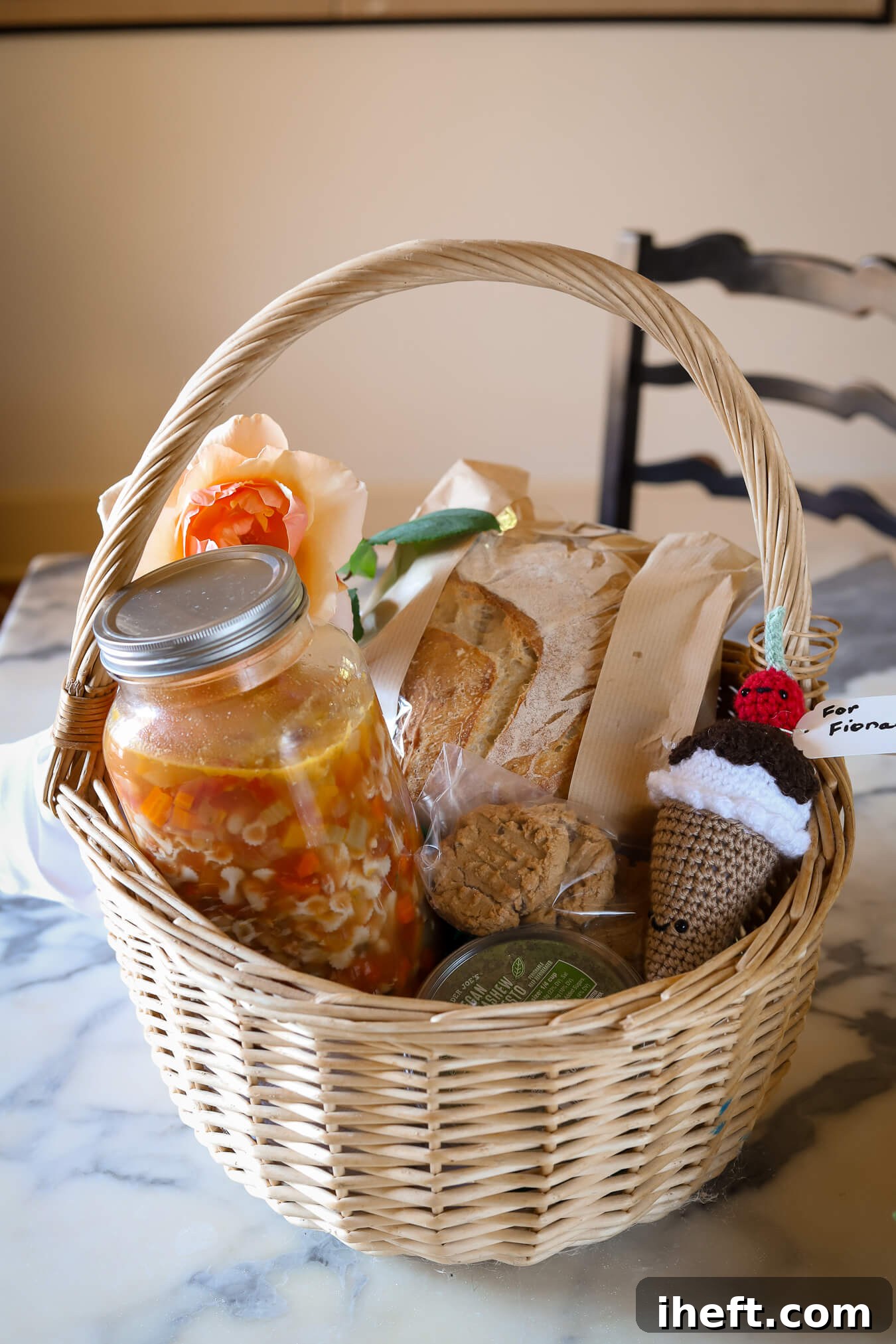 A basket filled with a mealtrain dinner. This includes minestrone, homemade sourdough bread, pesto, and peanut butter cookies. 