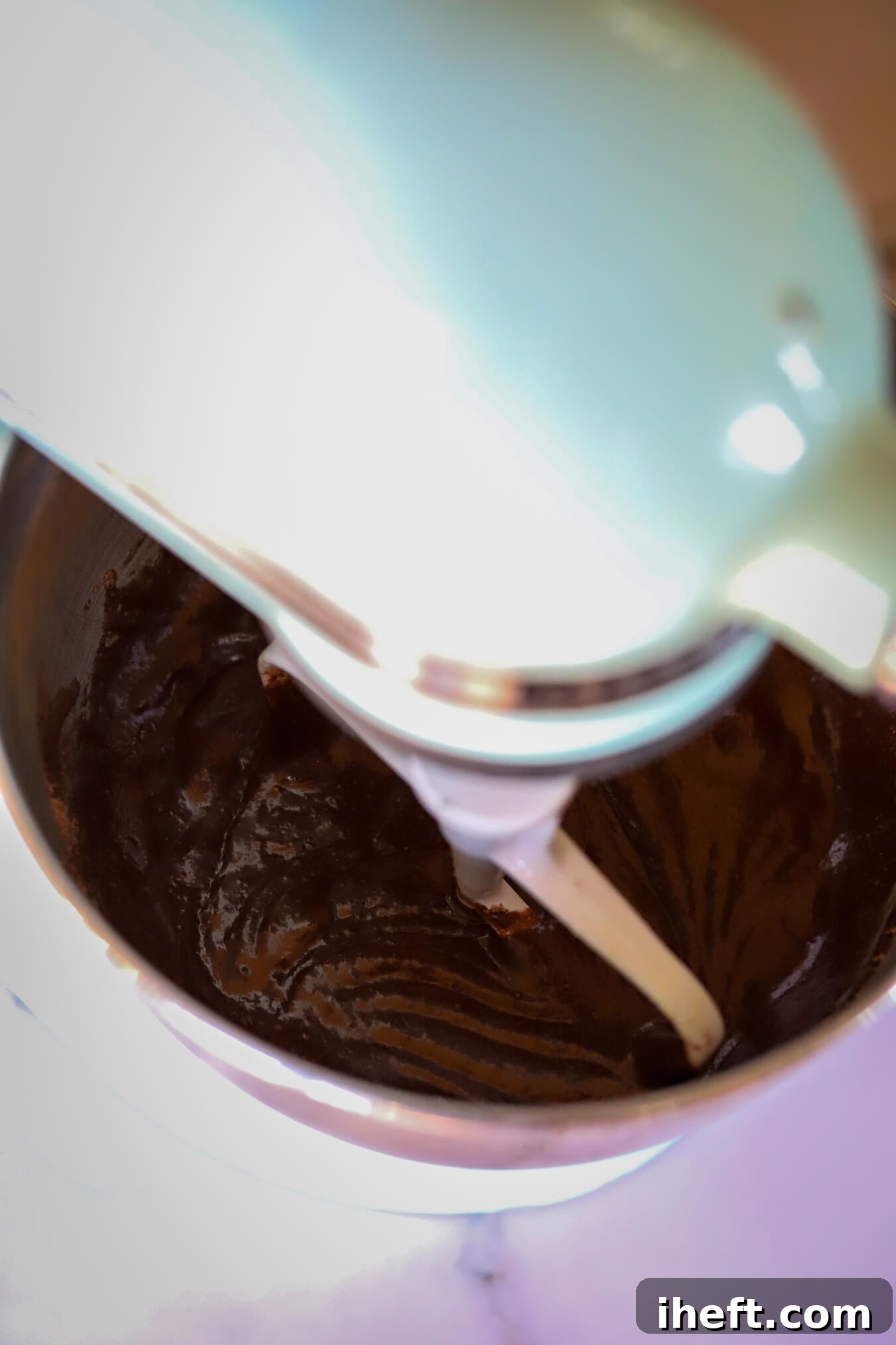 The luscious batter for Ina Garten's Chocolate Cake is perfectly mixed in a KitchenAid stand mixer with the paddle attachment. This captures a key step in the process of creating a perfectly moist chocolate cake.