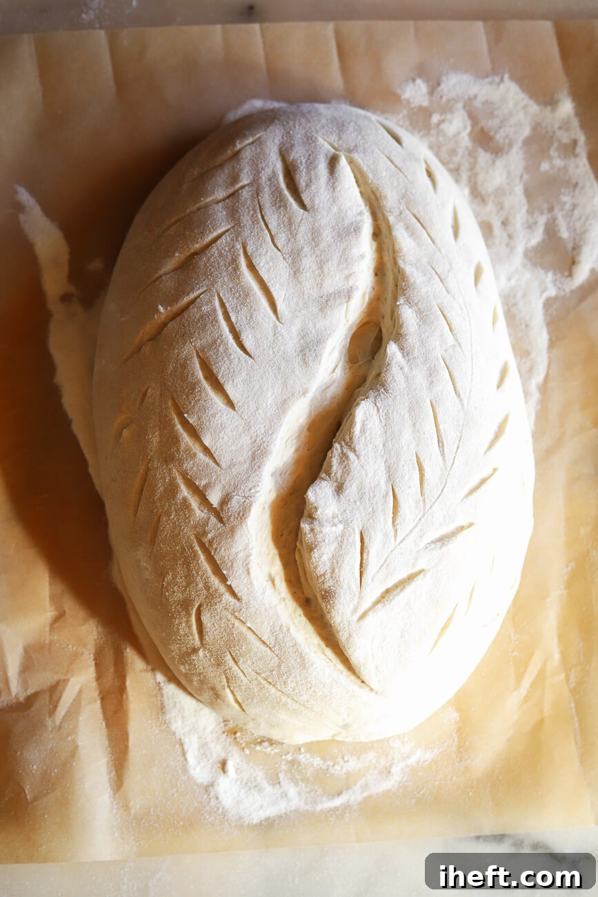 Homemade sourdough batard dough in an oval banneton proofing basket lined with a pink cloth for a final ferment.