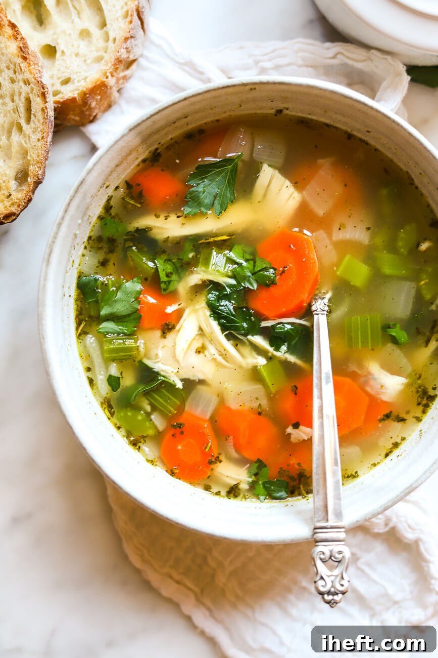 A healthy gluten free chicken vegetable soup with carrots, celery, bone broth, and rotisserie chicken in a ceramic bowl. 