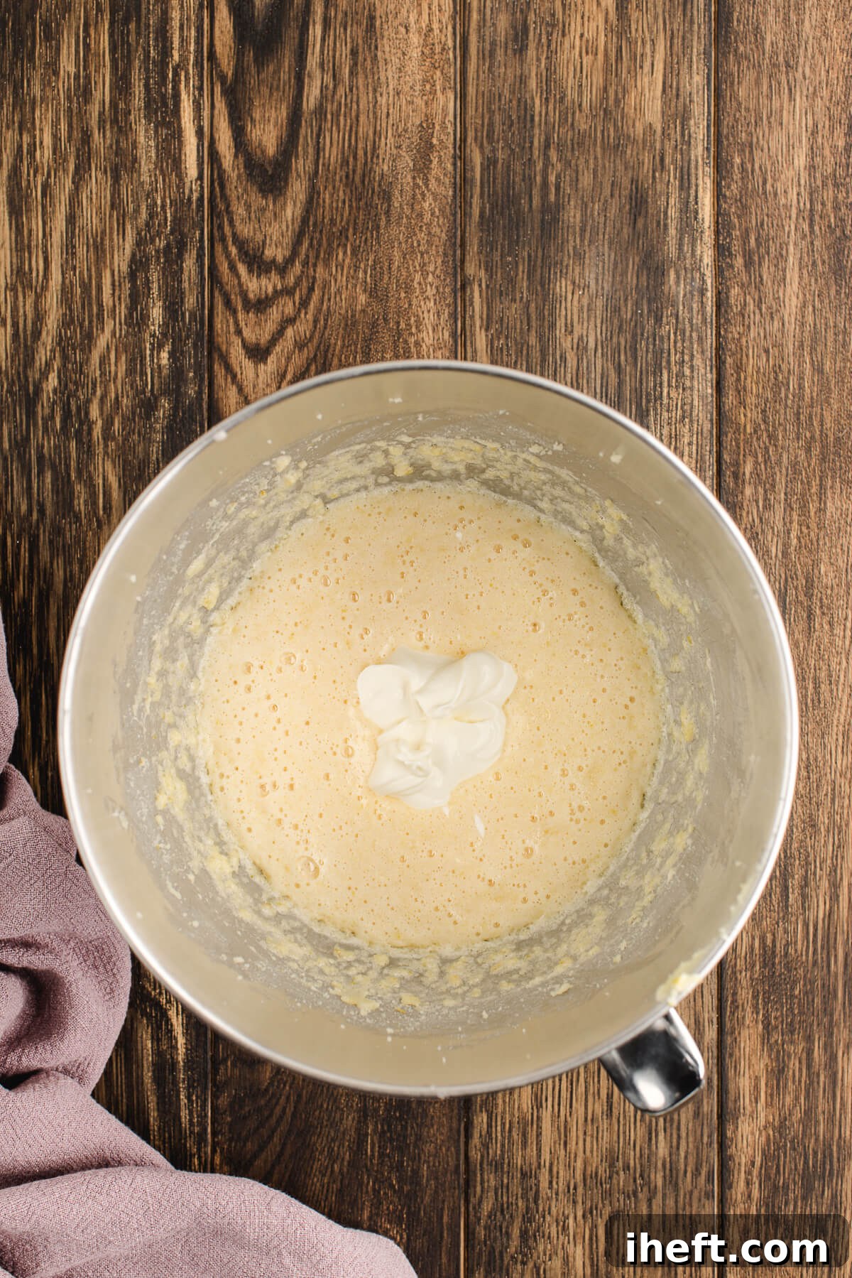 Sour cream and lemon juice are added to a stand mixer making sour cream coffee cake.