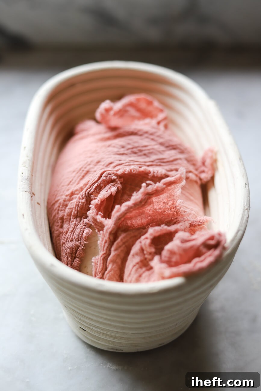 Sourdough bread dough in a banneton basket lined with pink thin napkin.