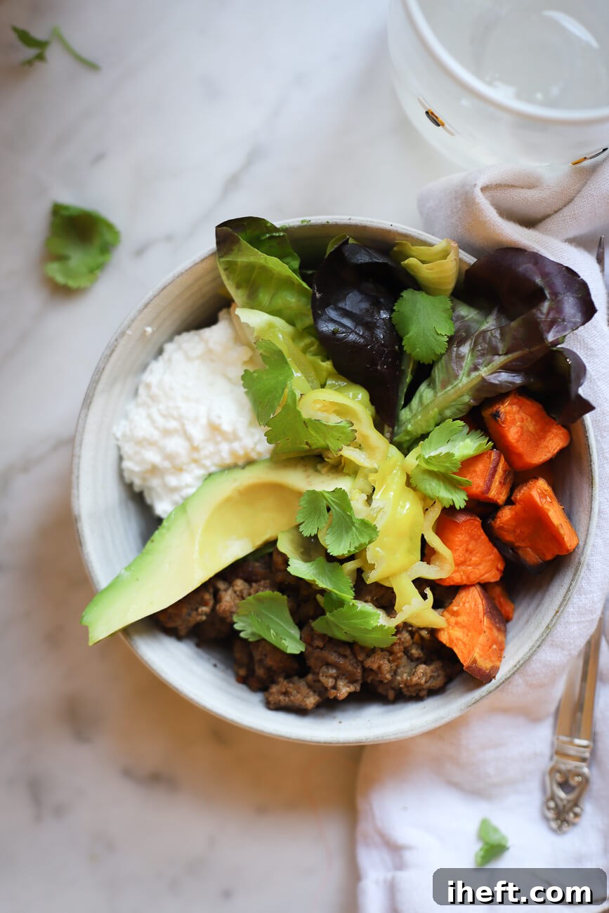 A nutritious high protein meal prep bowl with ground beef, sweet potato, avocado, greens, and cottage cheese. 