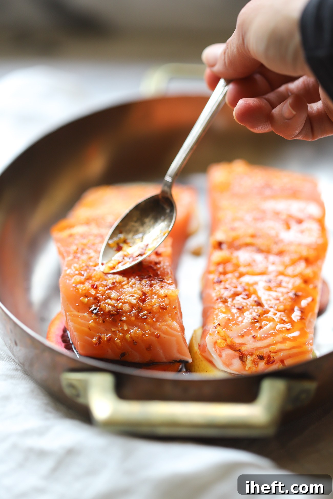 Trader Joe's Crunchy chili onion is spooned on top of raw wild salmon filets in a copper baking dish. 