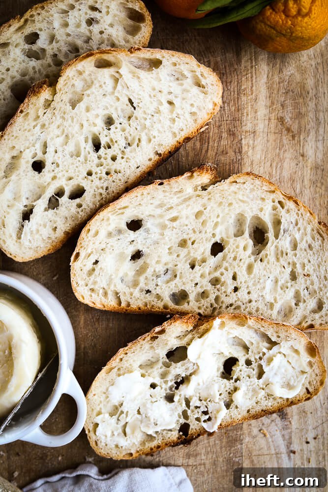 Slices of homemade sourdough bread served with butter on a wooden cutting board.
