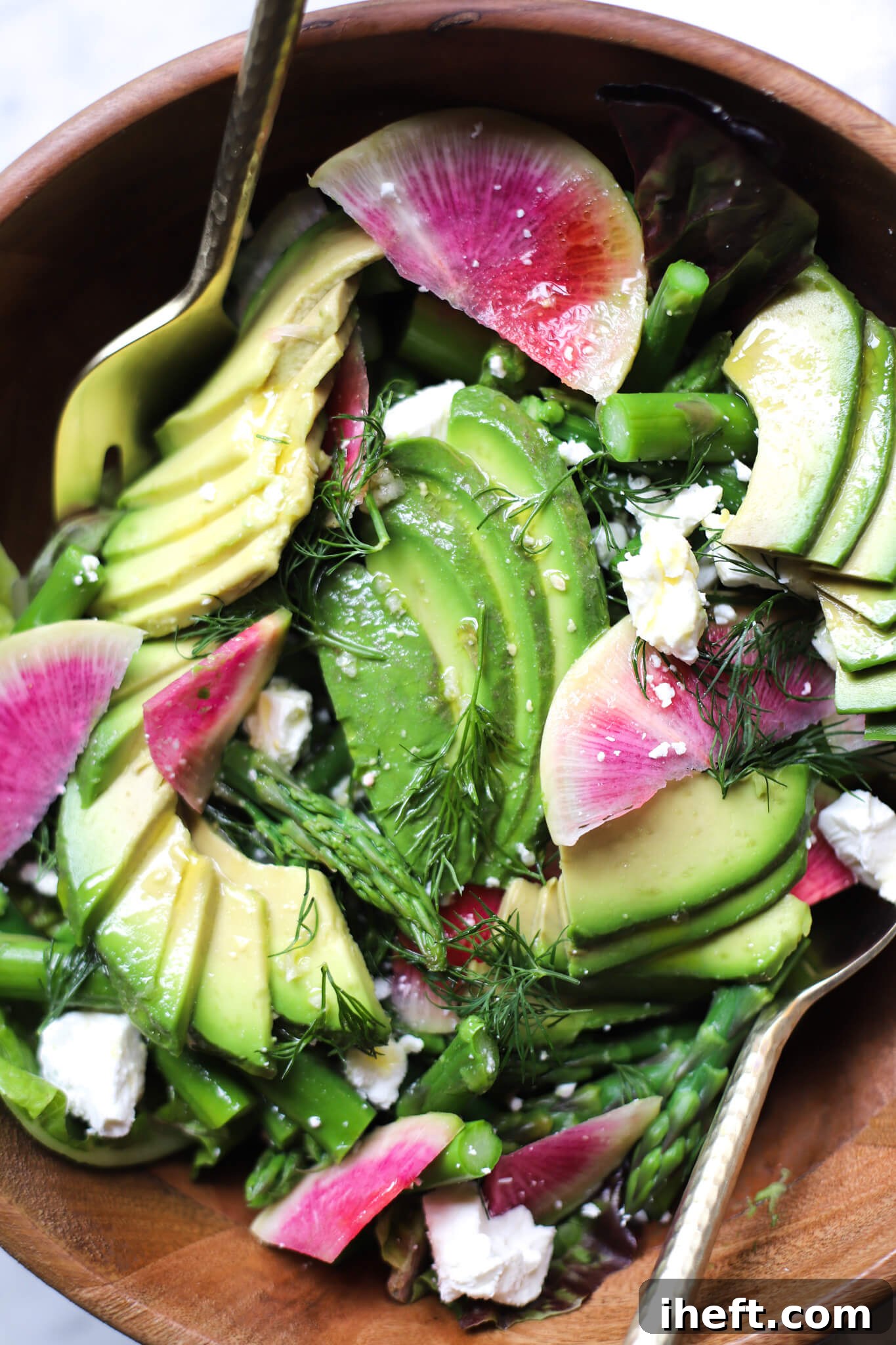 A spring salad with asparagus, avocado, feta cheese, watermelon radish, and dill.