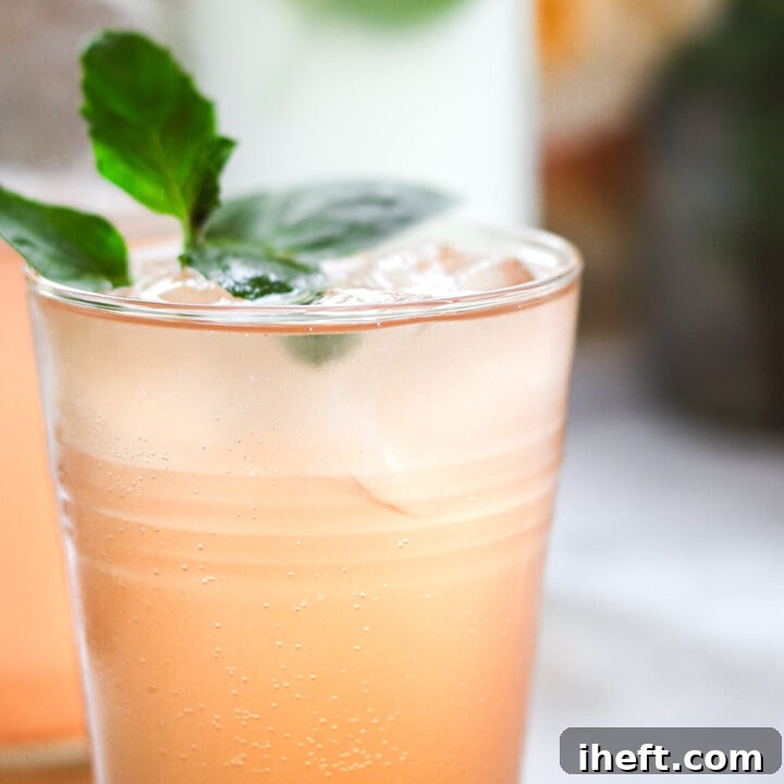 Peach flavored water kefir after the second ferment in a glass with ice garnished with mint. A refreshing homemade probiotic soda recipe.