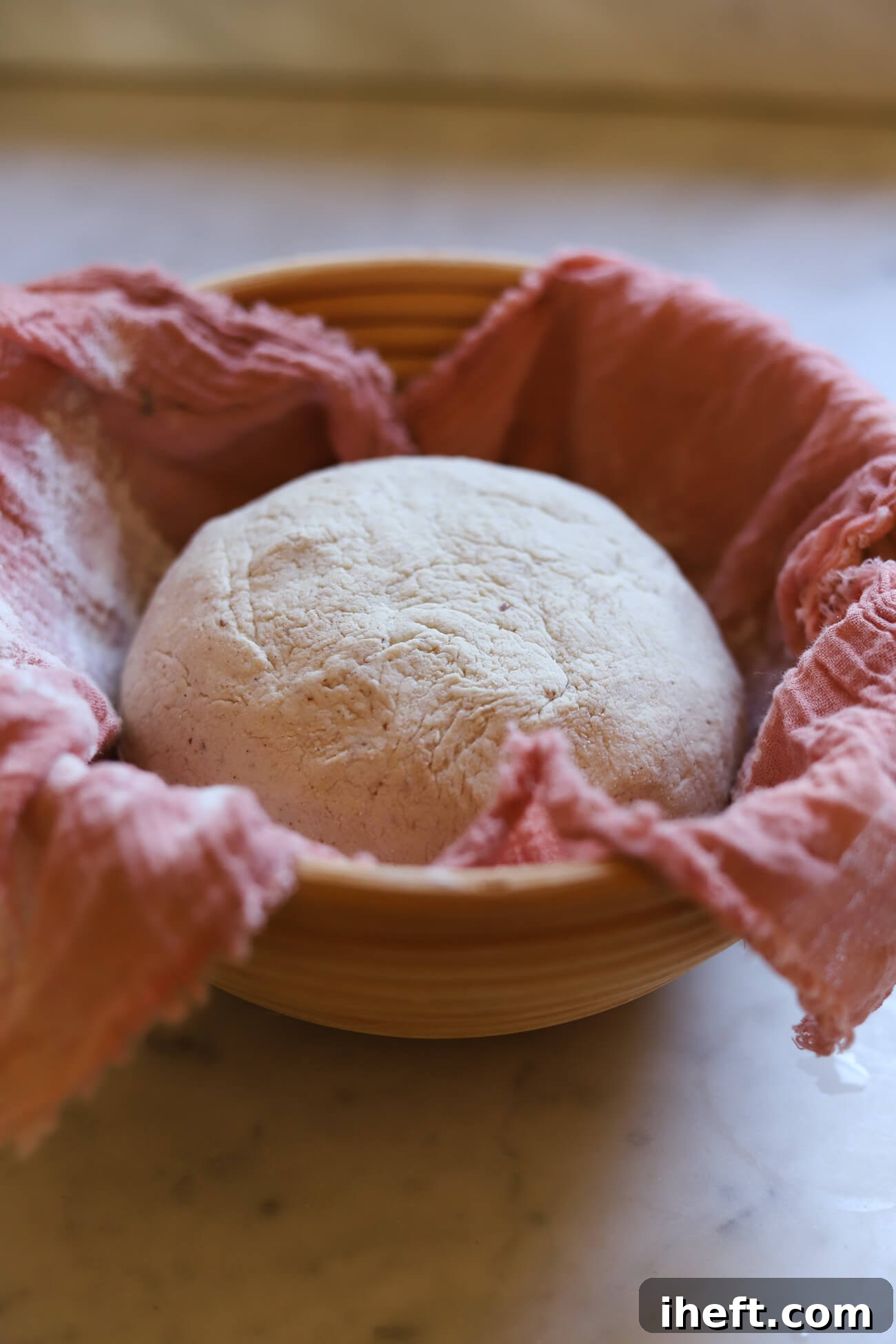 Sourdough dough ball in a pink fabric lined proofing basket.