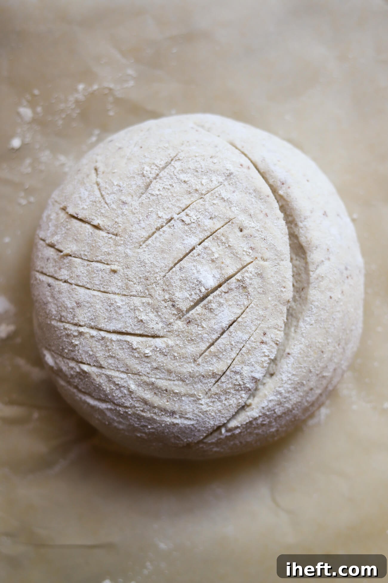 How to score gluten-free sourdough boule. A ball of unbaked sourdough dough with a deep score on one side and shallow decorative cuts on the other.