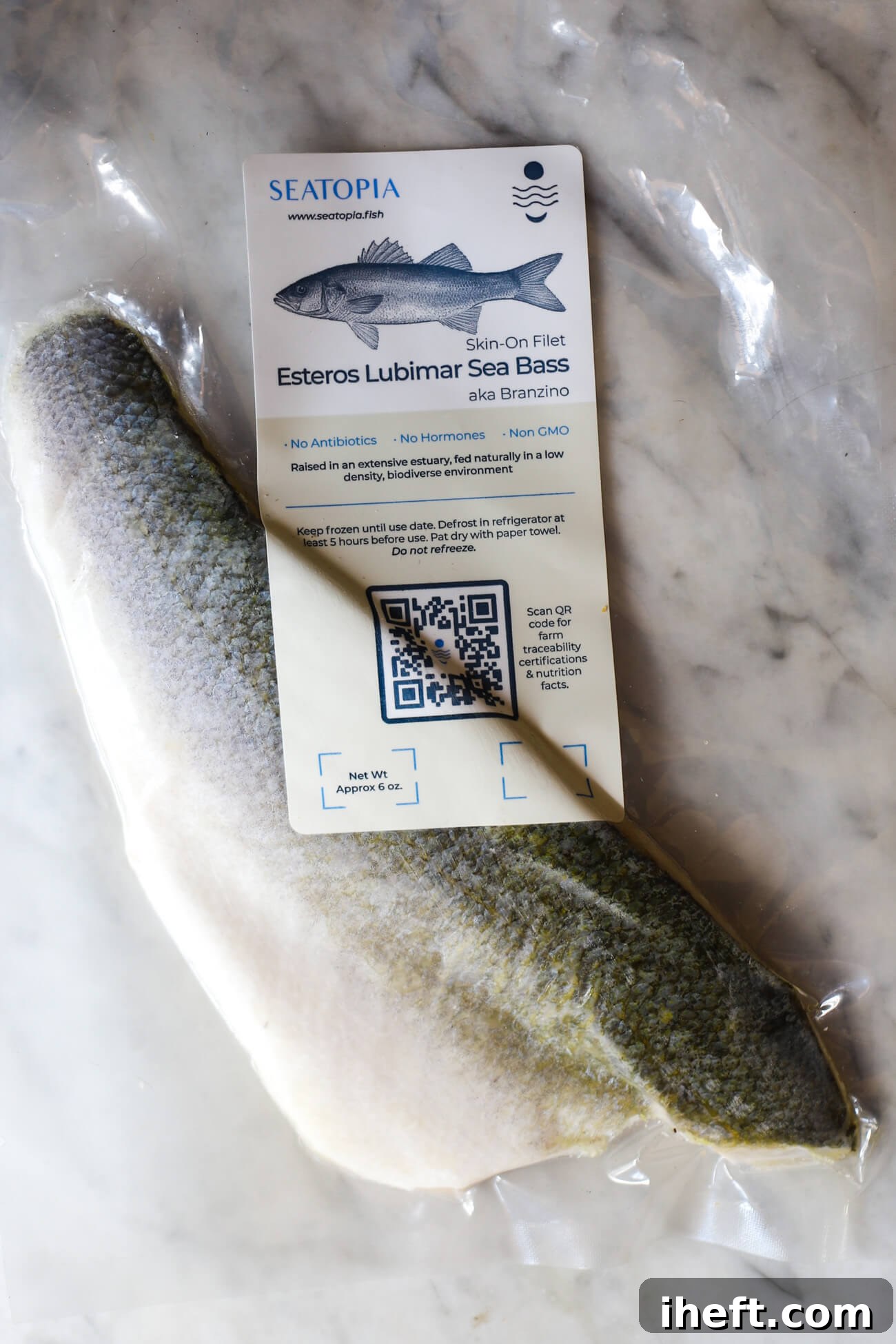 A neatly packaged box of frozen branzino fillets from Seatopia displayed on a pristine white marble countertop, highlighting the convenience and quality of specialty seafood delivery.