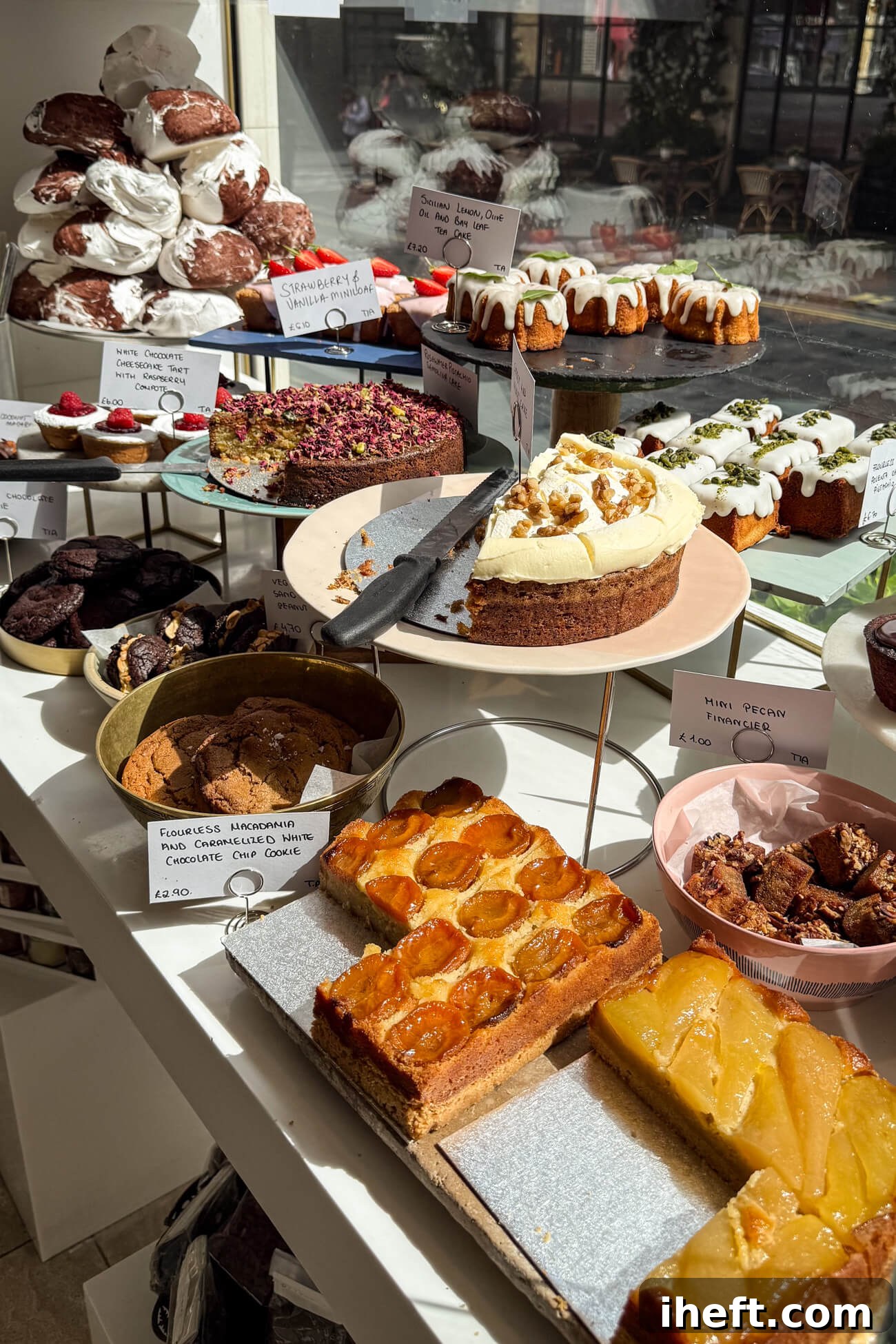 An inviting array of beautiful desserts displayed in the window of Ottolenghi in Marylebone. Cakes, cookies, and meringues are artfully arranged, looking utterly delicious.
