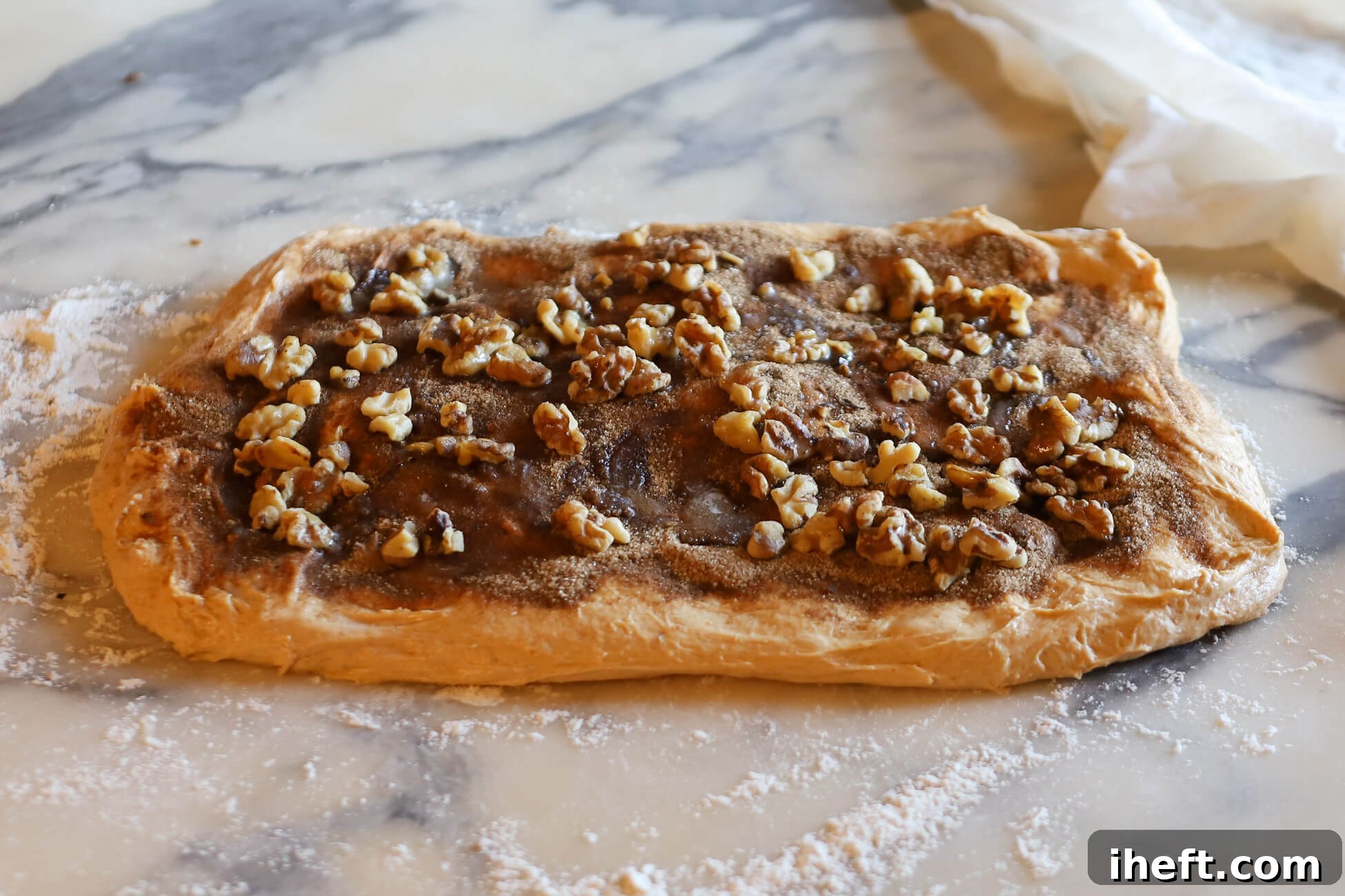 Pumpkin sourdough dough shaped into a rectangle and topped with cinnamon sugar and walnuts before shaping.
