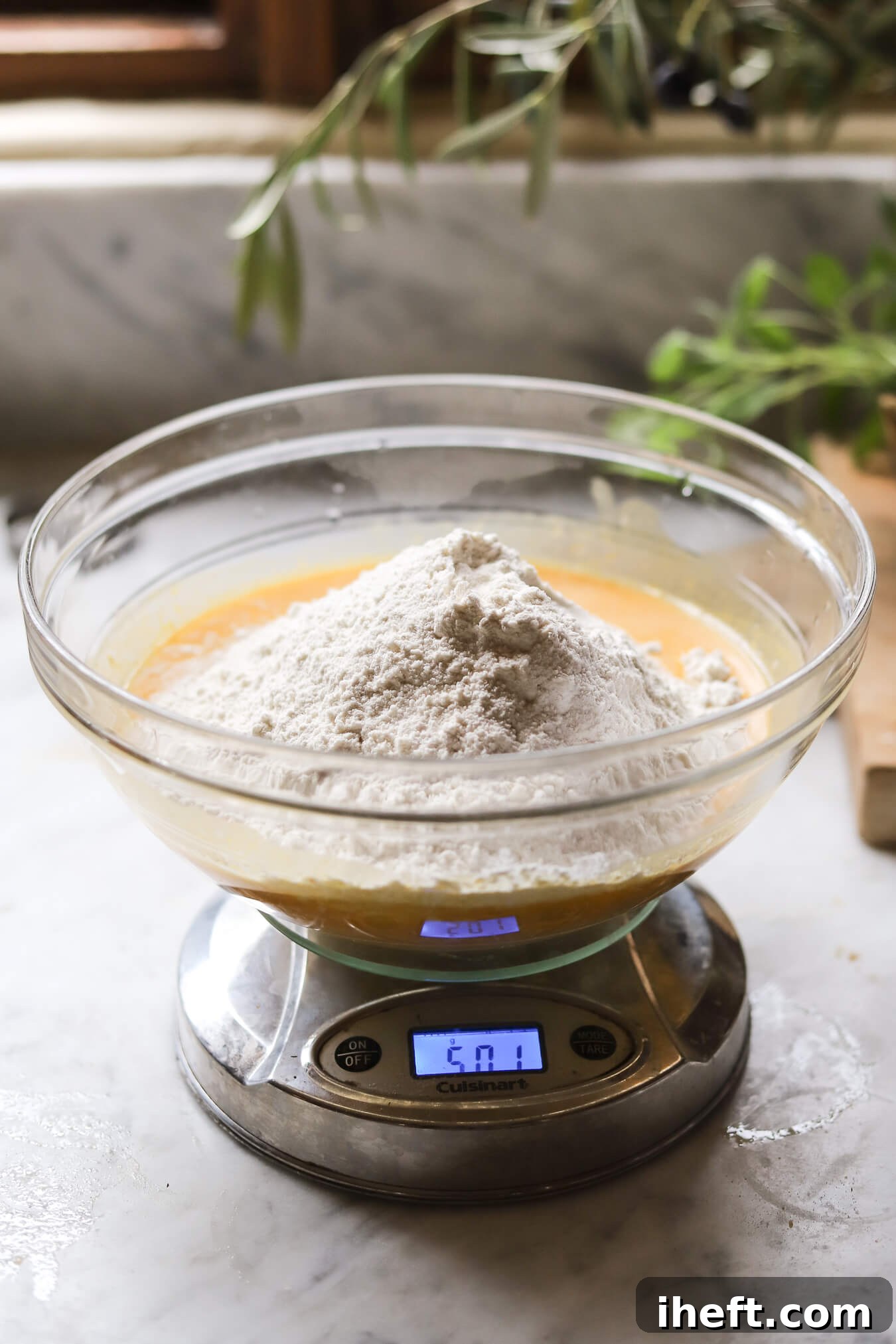 Mixing pumpkin sourdough dough ingredients in a glass bowl on a kitchen scale
