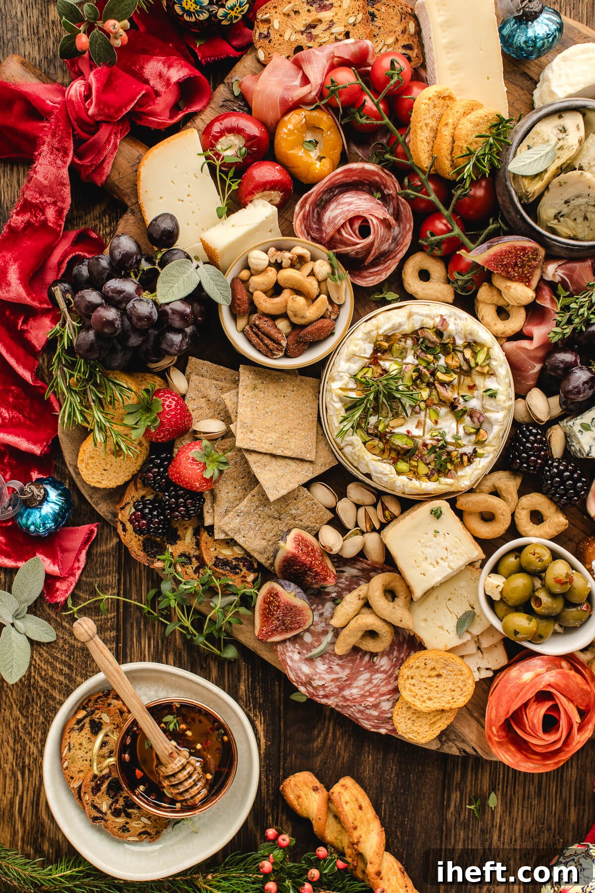 Holiday grazing board with brie, salami, crackers, figs, nuts, and Christmas decorations styled on a rustic wooden surface.