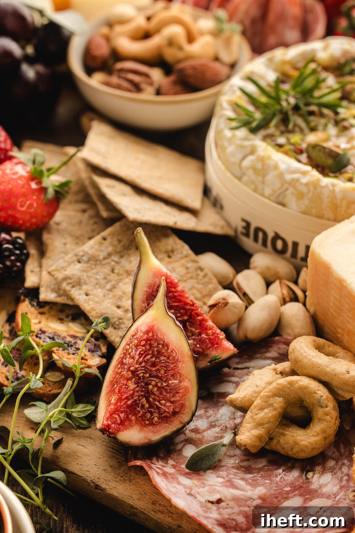Close-up of Christmas charcuterie board with fresh figs, crackers, brie, pistachios, berries, and festive holiday grazing ingredients. 