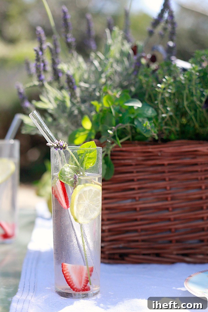 Beautiful water with fresh herbs, strawberries, and lavender form a kitchen herb garden centerpiece.