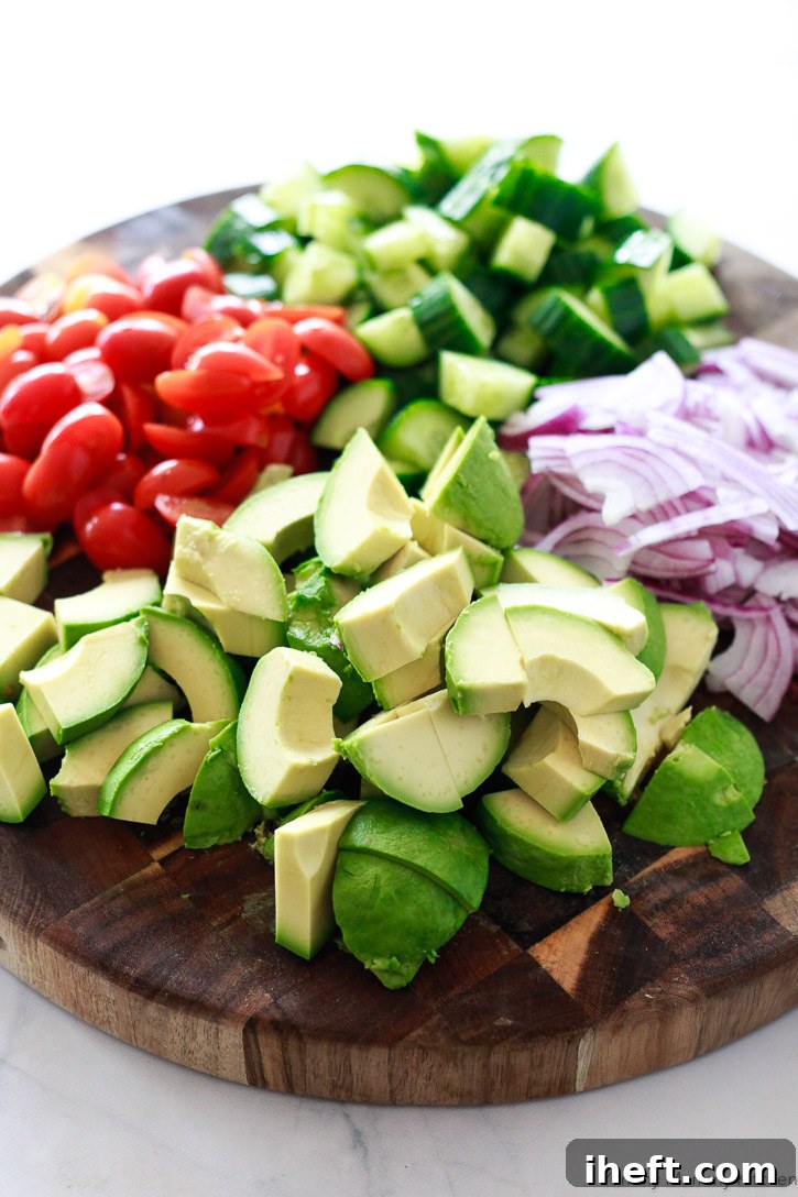 A close-up view of the fresh and simple ingredients used in this avocado salad recipe, including bright cherry tomatoes, crisp cucumber, and ripe avocados.