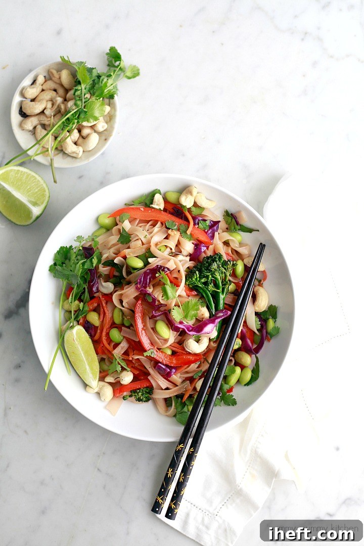 A vibrant bowl of homemade Vegan Rainbow Veggie Pad Thai, featuring rice noodles, broccoli, bell peppers, carrots, edamame, and chopped peanuts.
