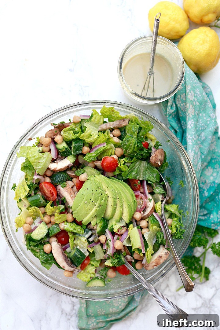 A vibrant Mediterranean salad generously drizzled with creamy lemon tahini dressing, featuring chickpeas, cucumbers, and tomatoes.