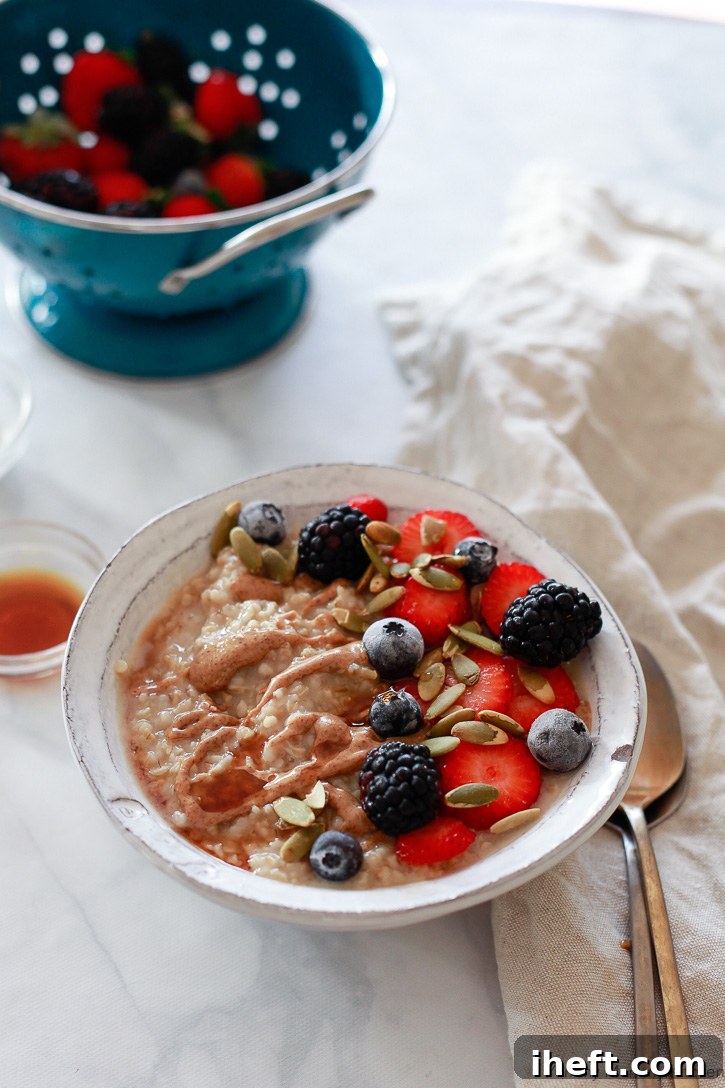 This comforting bowl of steel cut oats, prepared in a slow cooker, is beautifully topped with a vibrant medley of fresh berries.