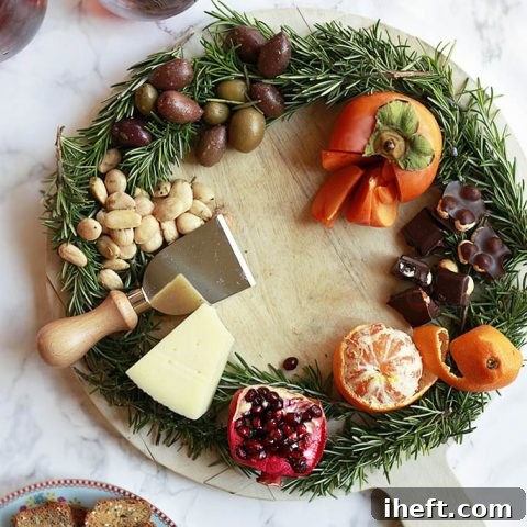 Beautiful wreath cheese board with Marcona almonds, gourmet chocolate, vibrant citrus, and juicy pomegranate, arranged for a festive occasion.