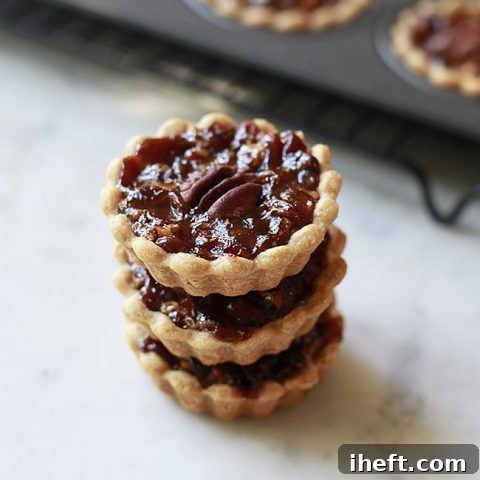 Three mini vegan pecan pies stacked up, showcasing their golden crusts and rich filling.