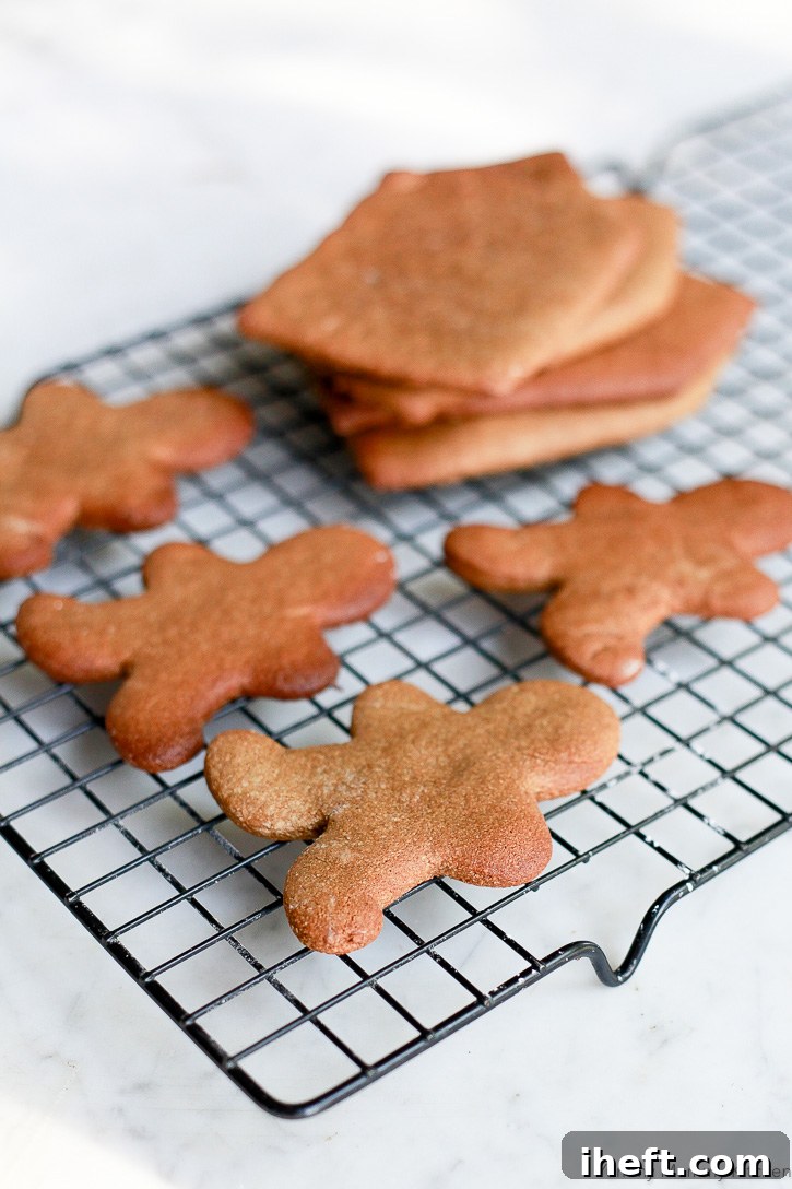 These charming gingerbread boy cookies are crafted from a paleo, gluten-free almond flour dough, cooling on a rack before their festive decoration.