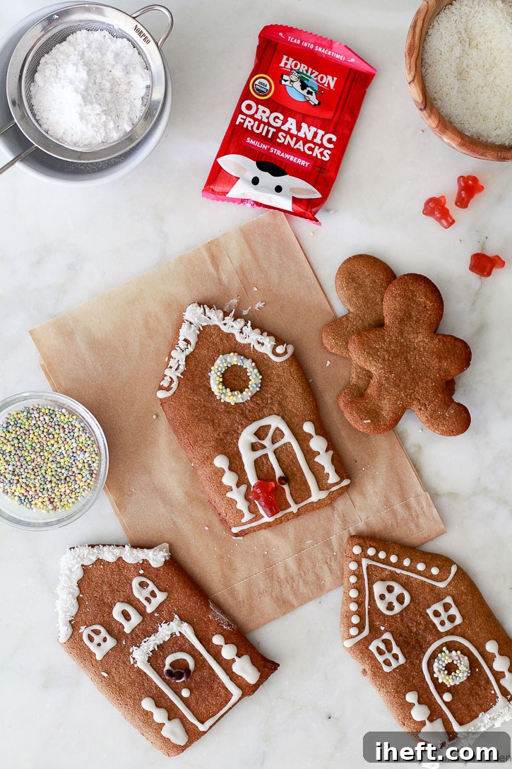 Naturally decorated gingerbread house cookies featuring dye-free ingredients like colorful sprinkles, wholesome fruit snacks, and delicate shredded coconut.