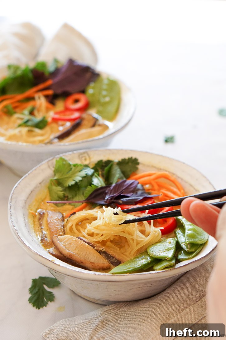 Beautiful vegan Thai coconut curry soup with rice noodles and vibrant vegetables, promising an easy and healthy dinner solution.