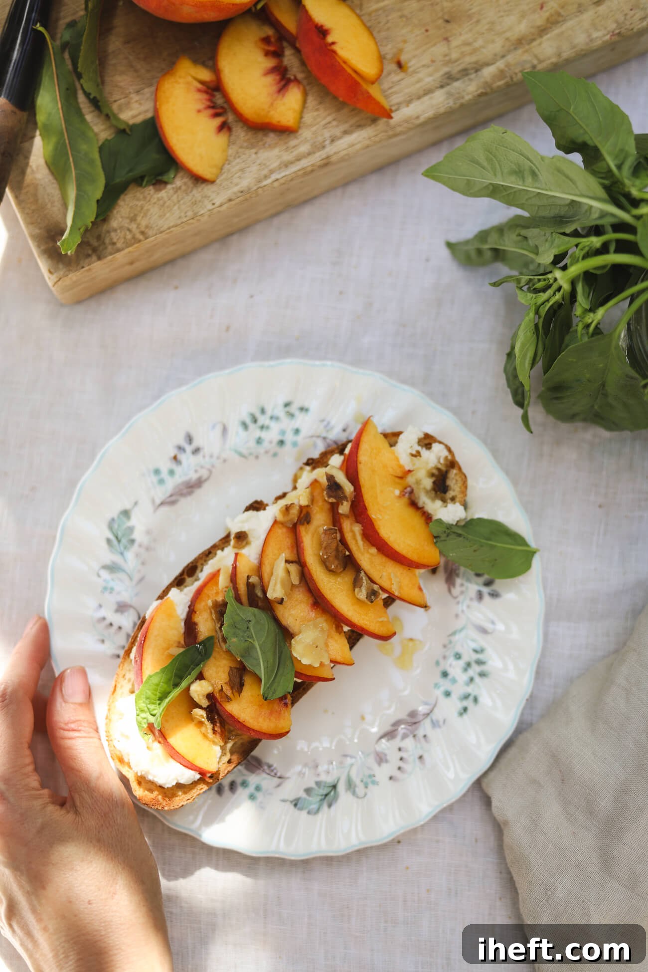 Peach Ricotta Toast with Whipped Honey Ricotta Peach ricotta toast made with homemade sourdough, whipped honey ricotta, fresh peaches, basil, toasted walnuts, and honey on a white plate.