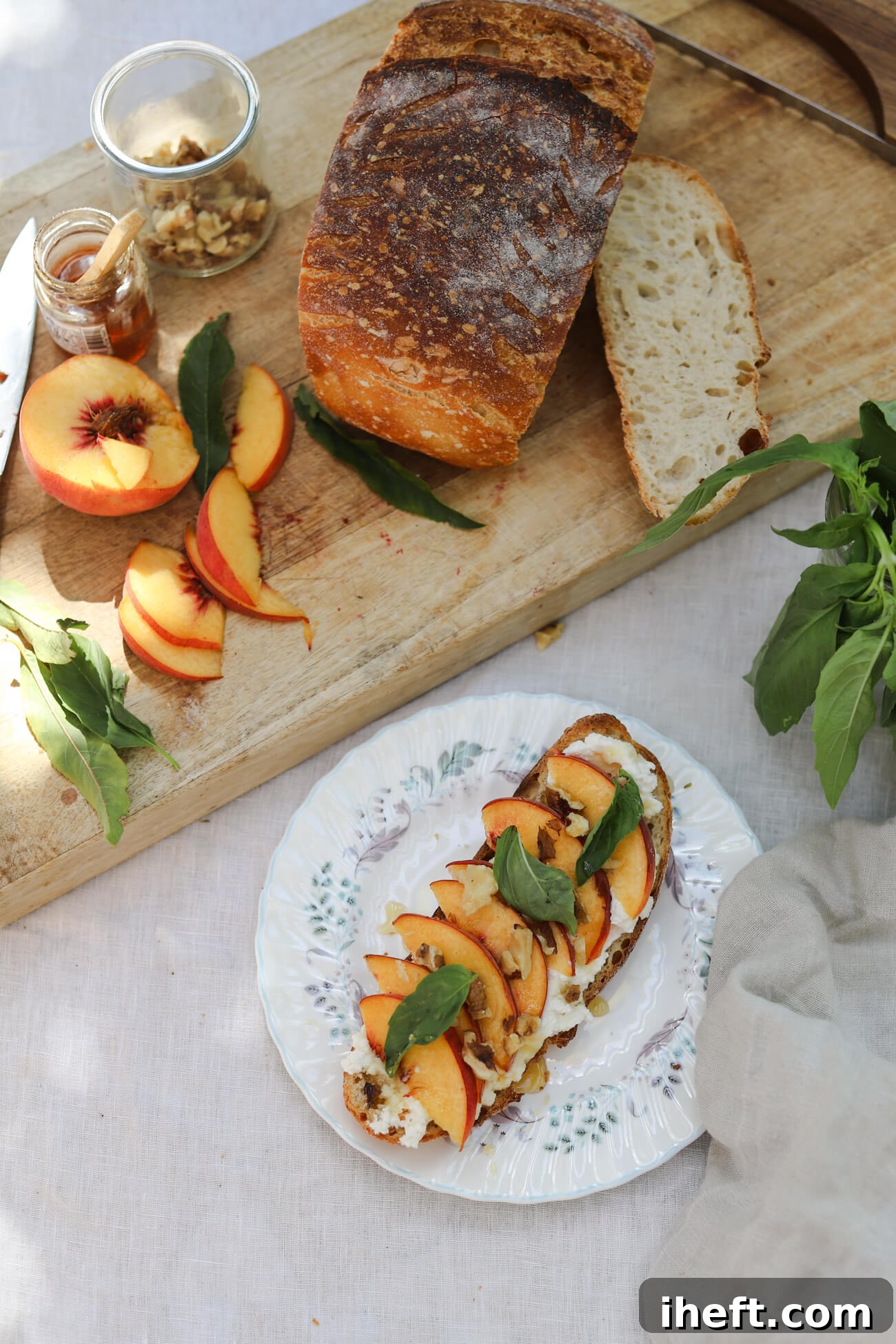 Peach Ricotta Toast with Homemade Sourdough Peach ricotta toast with homemade sourdough, fresh peaches, whipped honey ricotta, basil, and walnuts alongside the ingredients on a wooden board.