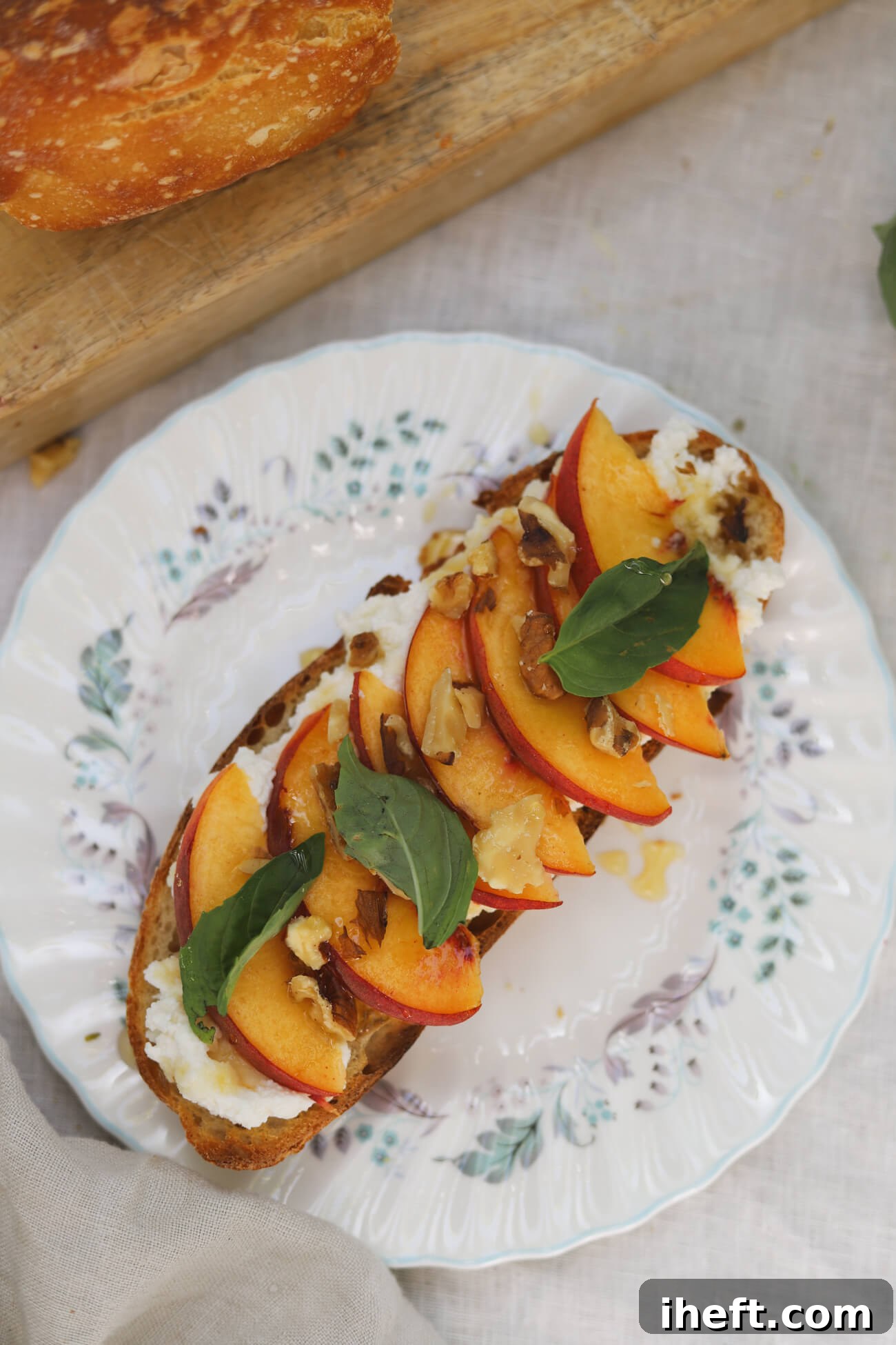 Peach Ricotta Toast with Homemade Sourdough Overhead view of peach ricotta toast on homemade sourdough topped with whipped honey ricotta, fresh peaches, basil, walnuts, and honey.