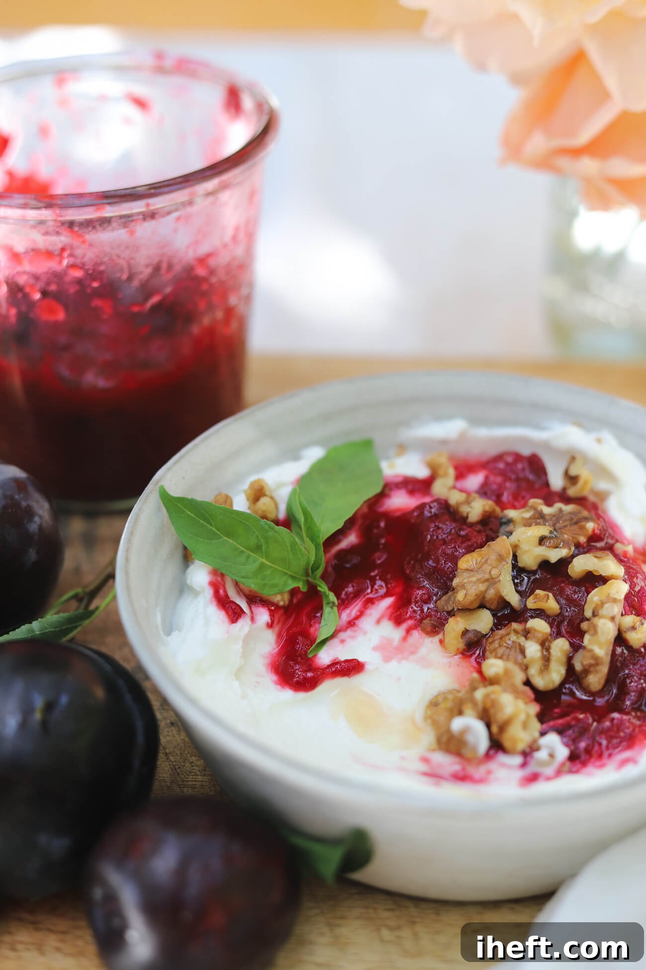Greek Yogurt Bowl with Roasted Plum Compote Greek yogurt bowl topped with roasted plum compote and walnuts beside fresh plums and a jar of compote