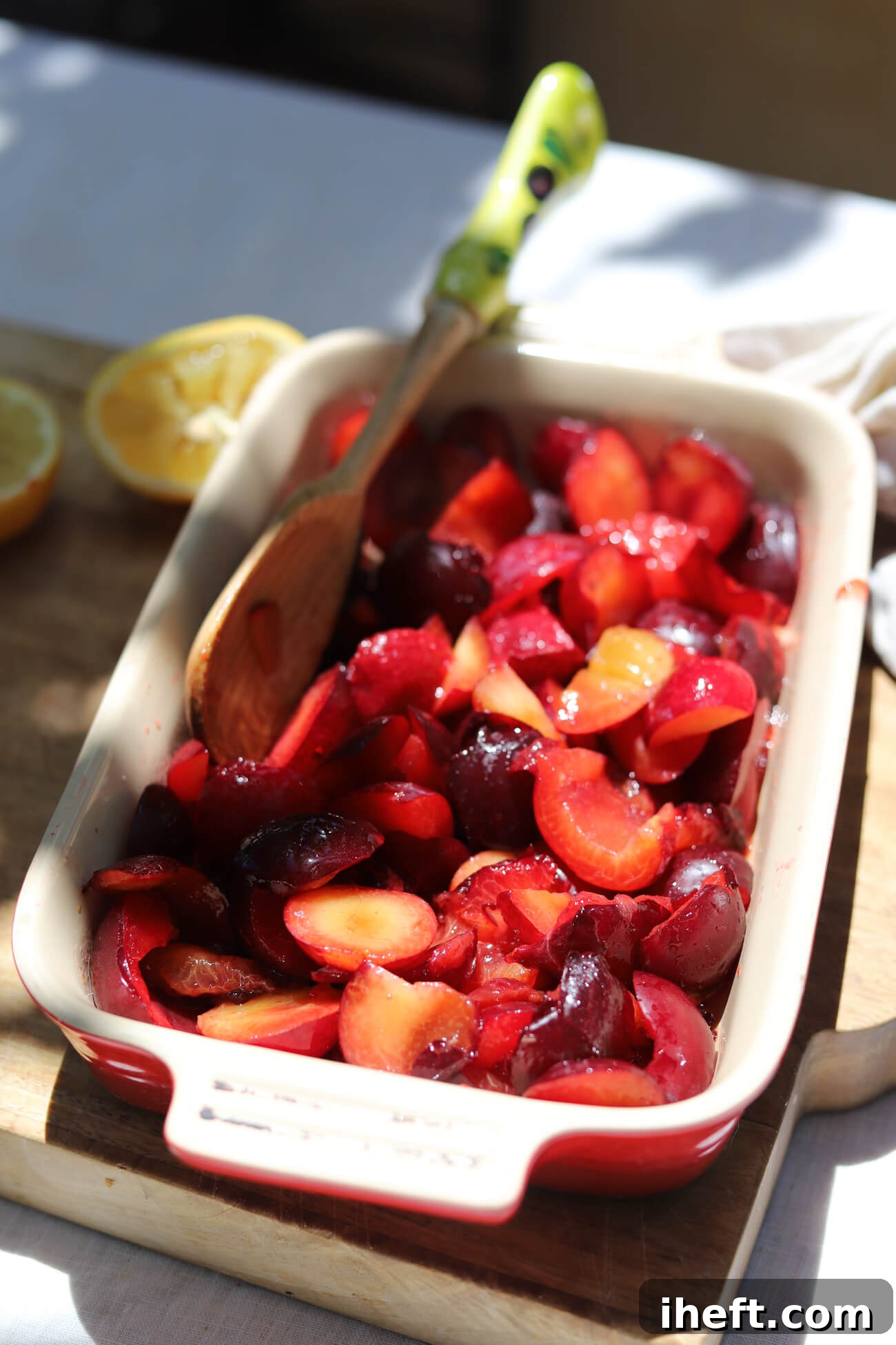 Plums Before Roasting for Plum Compote Fresh plums tossed with maple syrup and lemon juice in a baking dish before roasting for plum compote