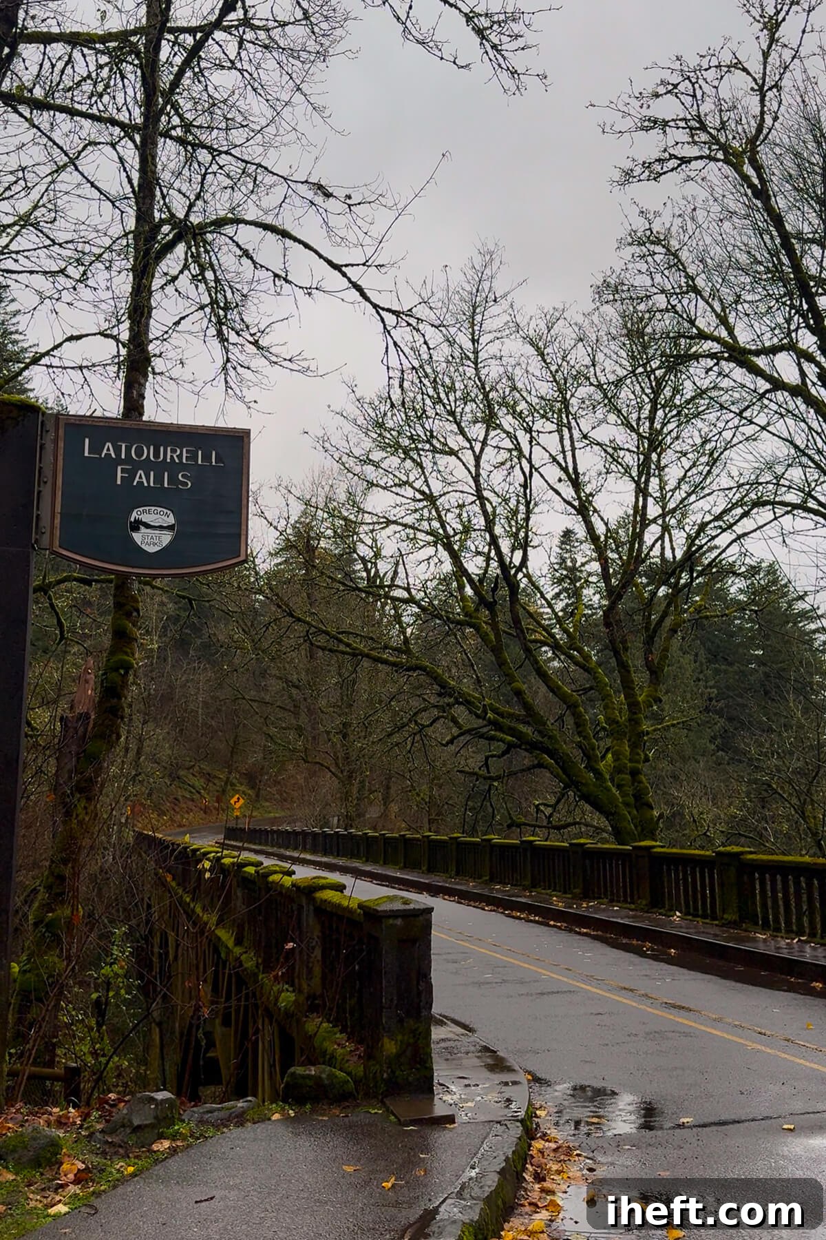 The sign for Latourell Falls on the Columbia River Gorge in Oregon. Moss covers the bridge on the historic road.